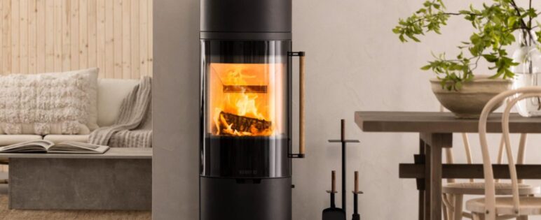 Svart, hög braskamin med brasa i ett ljust, nordiskt rum